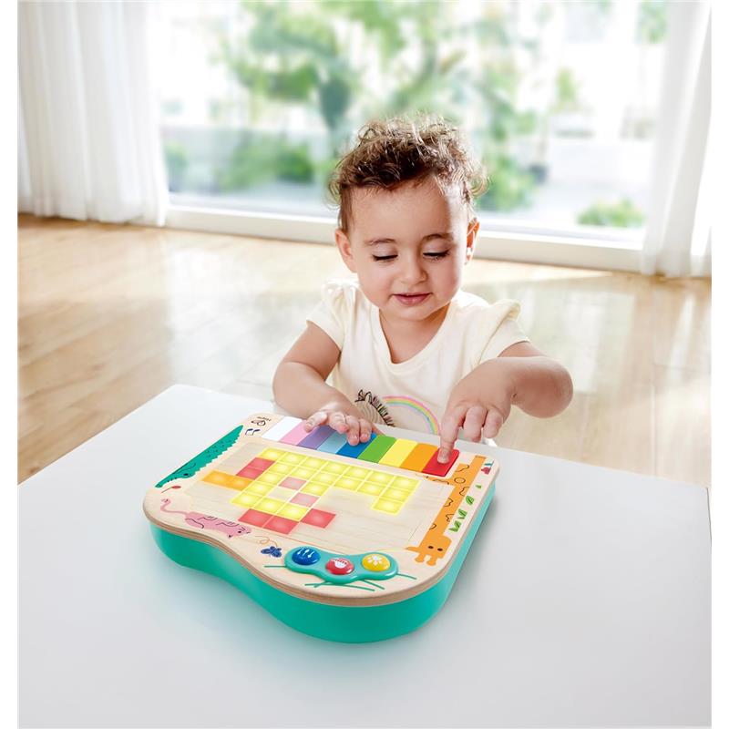 Toddler interacting with the Hape Dynamic Pixel Piano, pressing colorful keys while smiling, in a bright room.