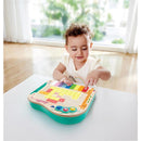 Toddler interacting with the Hape Dynamic Pixel Piano, pressing colorful keys while smiling, in a bright room.