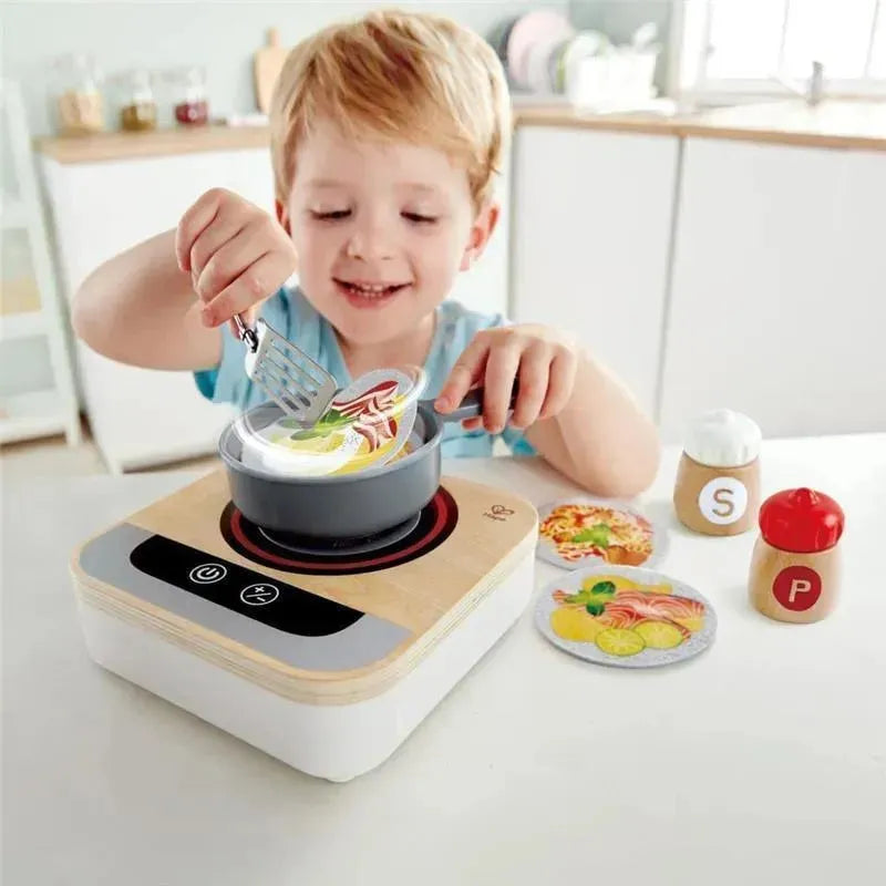 Wooden tabletop stove with fan, featuring a young child playing and cooking with toy food items and a spatula.