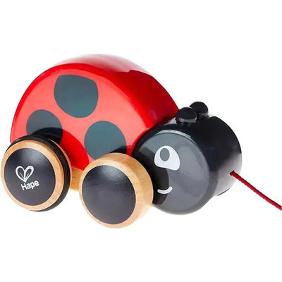 Wooden ladybug pull toy with red body, black spots, and cheerful face, featuring wooden wheels and a pull string.
