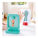 Interactive medical playset featuring a teal X-ray device displaying a hand silhouette, with a child’s hand visible.