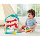 Toddler playing with Hape Melody Mansion Ball Run, featuring a colorful ramp and xylophone, smiling happily in a bright room.