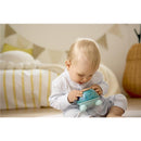 A baby in pajamas interacts with the Hape Music Turtle toy, focusing on its colorful musical features.