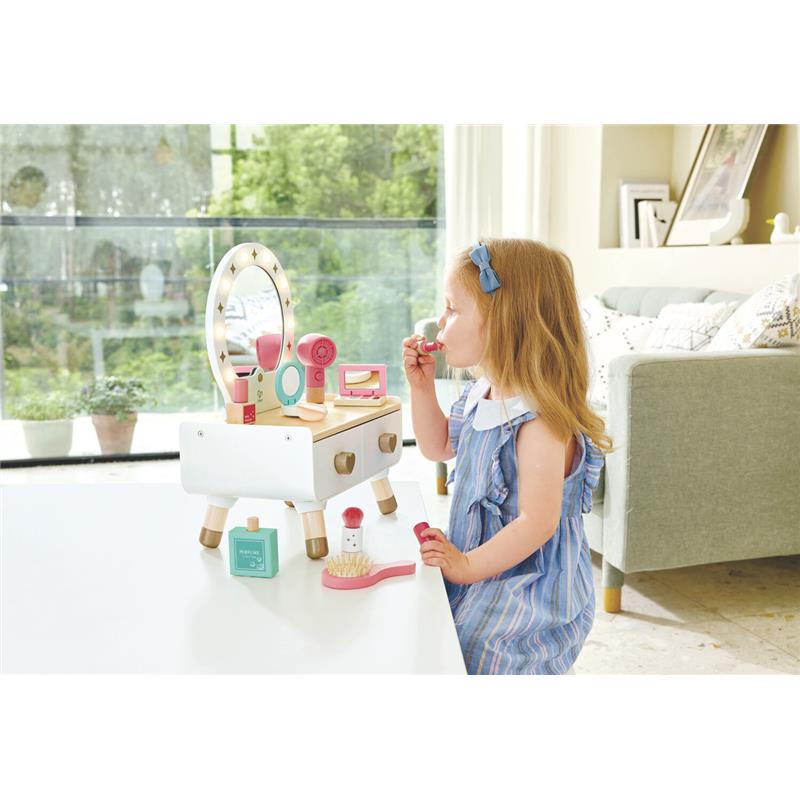 Child applying lipstick at Hape My Stylish Dressing Table, featuring a mirror, makeup accessories, and a light wooden design.