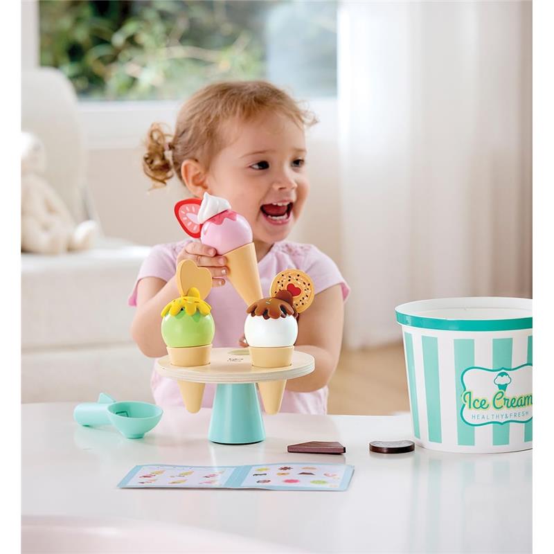 A young girl joyfully holds an ice cream cone while three colorful toy ice cream cones are displayed on a wooden stand.