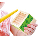 Child holds a Hape Stacking Music Set with a green musical notes design, using a yellow stick to play.