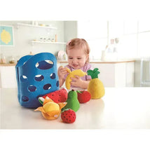 A toddler interacts with colorful felt fruits, including a banana and pineapple, alongside a blue felt basket.