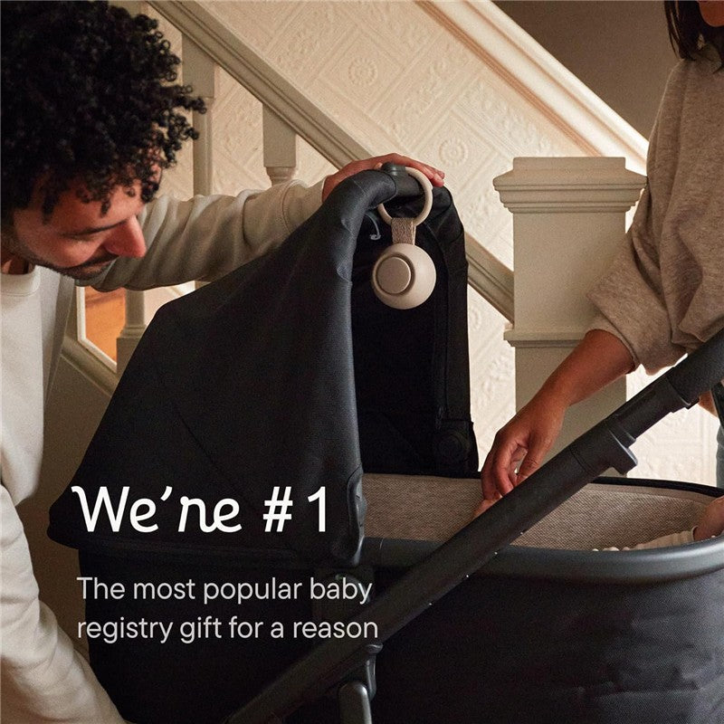 Hatch Go Portable Sound Machine in greige being used with a stroller by a man and woman indoors near stairs.