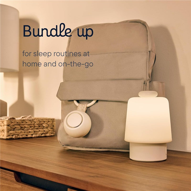 Hatch Go Portable Sound Machine in greige next to a soft lamp and a beige backpack, promoting sleep routines at home and on-the-go.