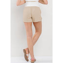 Khaki linen blend maternity shorts with an elastic band, styled with a white top and sandals, viewed from the back.