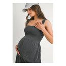 Ribbed smocked maternity knit romper in charcoal worn by a smiling woman, gently touching her pregnant belly, with a gray cap.
