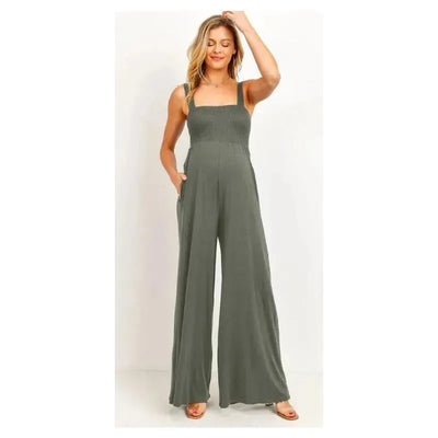 Smocked olive green maternity jumpsuit with a square neck and flared legs, featuring side pockets and a relaxed fit.