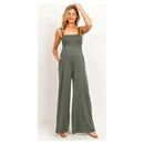 Smocked olive green maternity jumpsuit with a square neck and flared legs, featuring side pockets and a relaxed fit.