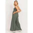 Olive green square neck smocked maternity jumpsuit with flared legs, model posing with hands in pockets.