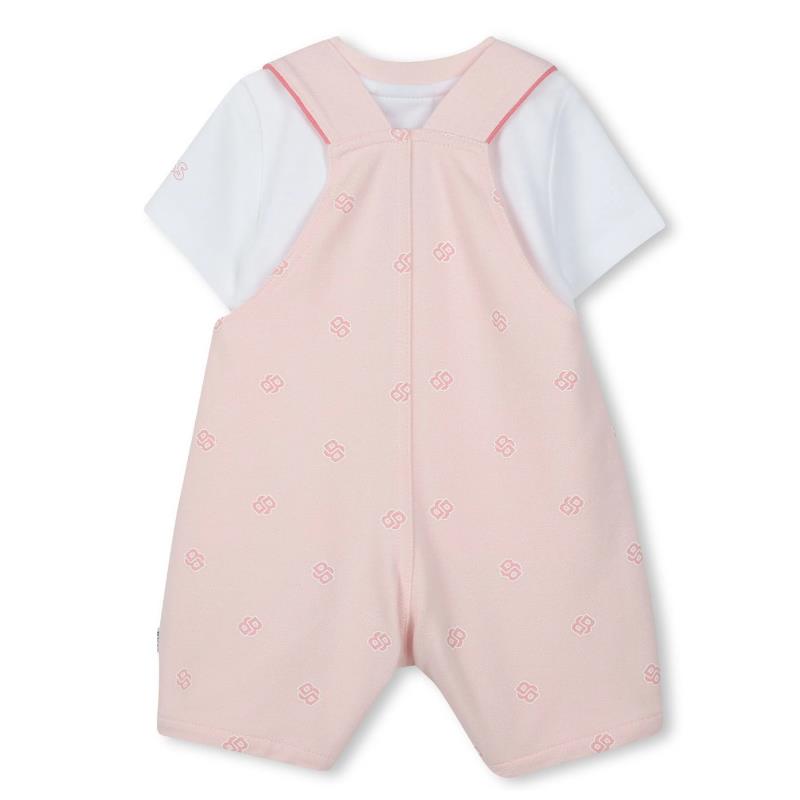 White t-shirt under pink dungarees featuring a subtle logo pattern, suitable for baby girls.