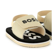 Beige Hugo Boss sandals featuring a Boss logo, with an open design and a black sole.