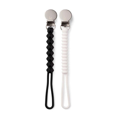 Black and white silicone holders with clips, designed for pacifiers, featuring a textured black piece and a smooth white piece.