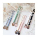 Silicone pacifier holders in pastel colors with clips, featuring textured designs and a black/white color scheme.