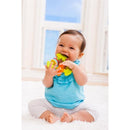 Baby smiling while chewing on a colorful Infantino Chewy Activity Teether, sitting on a soft surface in a bright room.