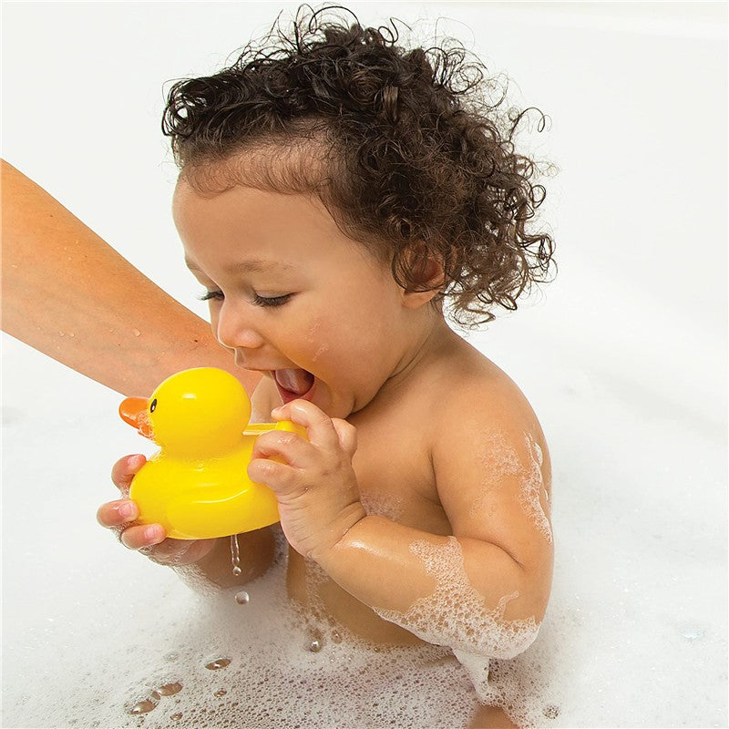 Toddler enjoying bath time, holding a yellow rubber duck while playing in a soapy bath.
