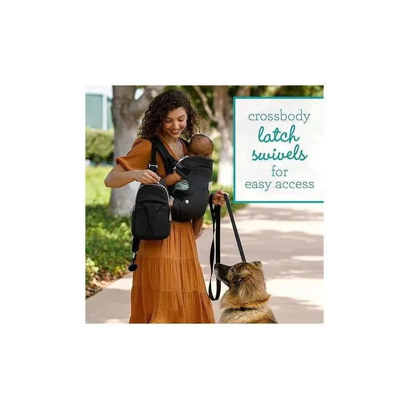A woman in a brown dress uses the Infantino Flip 4-In-1 Convertible Carrier while holding a baby, with a dog beside her.