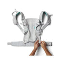 Teal Infantino Flip 4-In-1 Light & Airy Convertible Carrier with adjustable straps and a curved seat, being fitted by hands.
