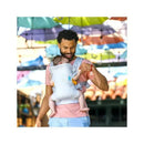 A man smiles while wearing a teal Infantino Flip 4-In-1 Convertible Carrier with a baby securely positioned in front.