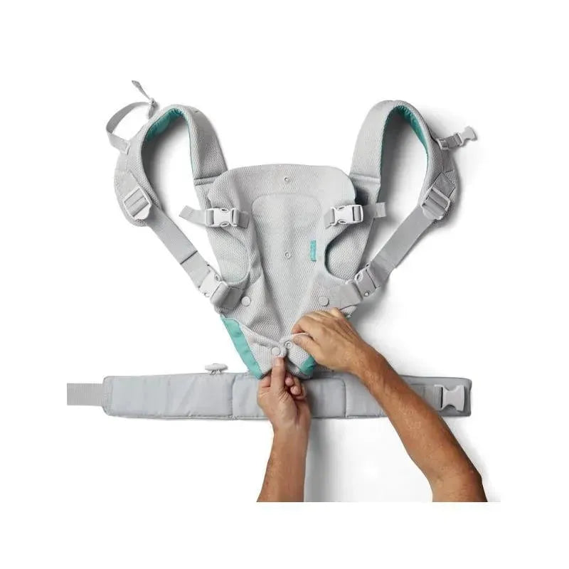 Teal and gray Infantino Flip 4-In-1 convertible carrier, being adjusted by a hand, showcasing adjustable straps and button features.