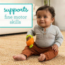 Infantino Handy Dandy Teething Mitt in orange held by a smiling toddler, promoting fine motor skills development.