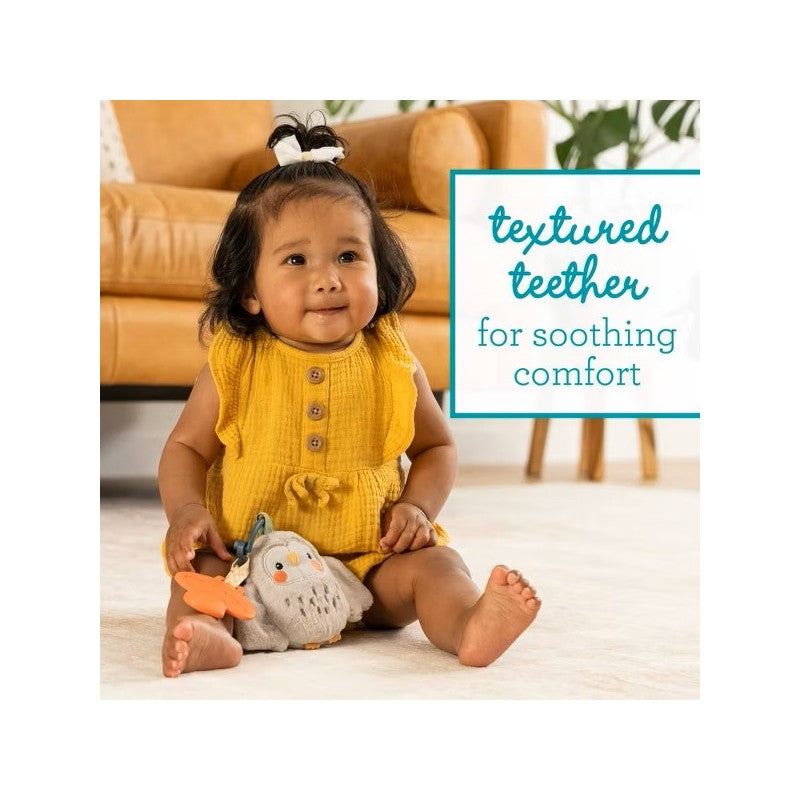 Smiling child in a yellow outfit sits with Infantino Mini Plushy Pal & Teether, Olive the Owl, and a textured flower teether.
