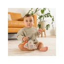Baby sitting on a carpet, holding an Infantino Mini Plushy Pal & Teether - Olive the Owl, with a relaxed expression.