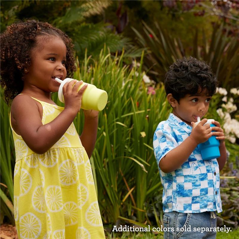 Two children enjoying drinks from colorful Infantino My 1st Tumblers in a garden setting, with vibrant greenery in the background.