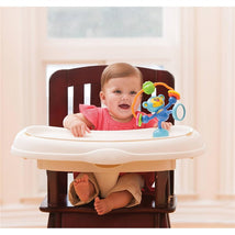 Baby seated in an Infantino Stick & Spin High Chair with a colorful monkey toy, smiling happily.