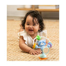 Smiling baby playing on a rug with an Infantino Stick & Spin Pal, Raccoon toy featuring bright colors and sensory elements.