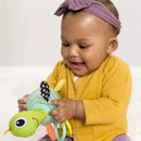 Infantino Textured Sensory Pal Turtle toy held by a cheerful baby wearing a yellow cardigan and purple headband.
