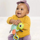 Smiling baby wearing a yellow sweater holds the Infantino Textured Sensory Pal Turtle toy, featuring colorful textures and rings.