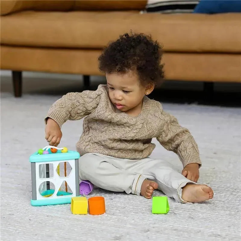 Toddler playing with Infantino Wee Wild Ones Activity Triangle, sorting colorful shapes on a soft rug.