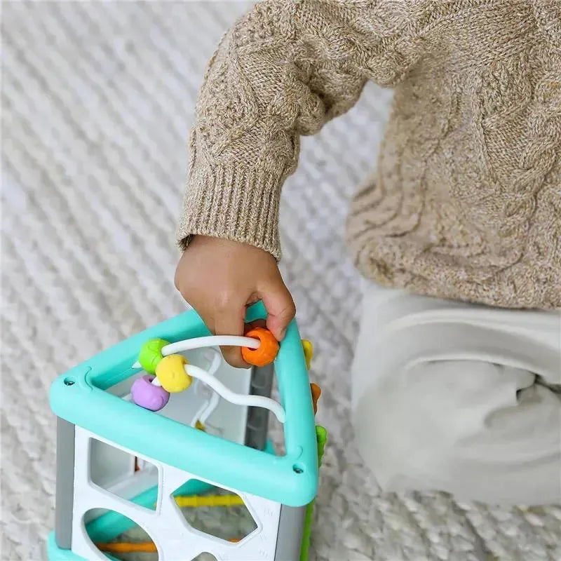 Child manipulates the Infantino Wee Wild Ones Activity Triangle, featuring colorful beads on wires for sensory play.