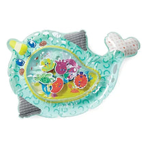 Water mat in the shape of a narwhal, filled with colorful, floating sea creature toys for infants to play with.