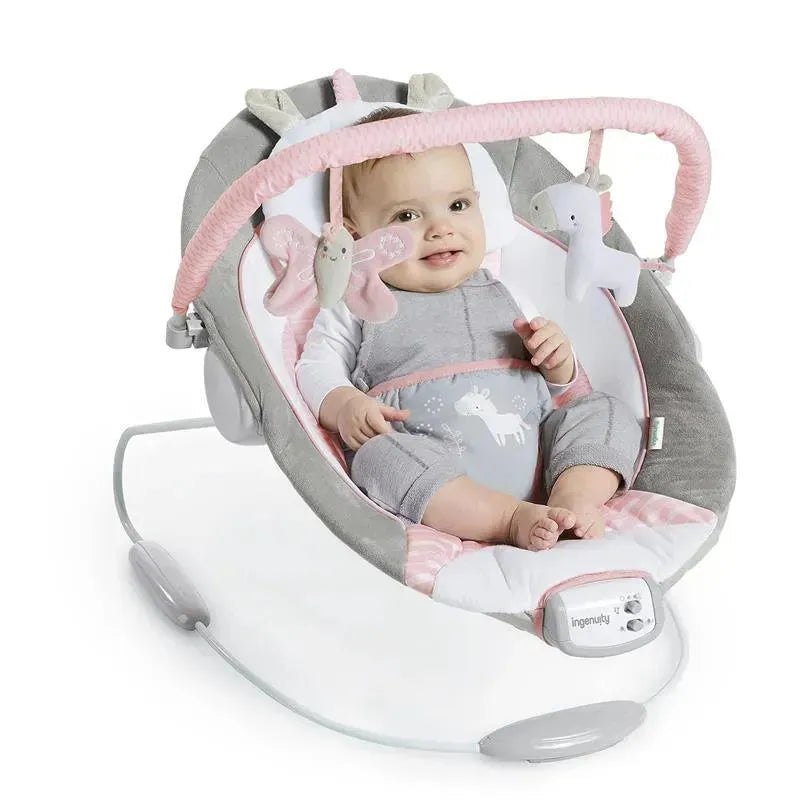 Soothing baby bouncer seat with a smiling infant, featuring a soft gray and pink design and hanging toys.