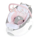 Infant seat in soft pink and gray, featuring a butterfly and unicorn toy, designed for soothing with vibrations.