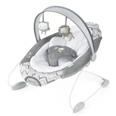 SmartBounce automatic baby bouncer seat in grey with plush material, a safety harness, and hanging plush toys.
