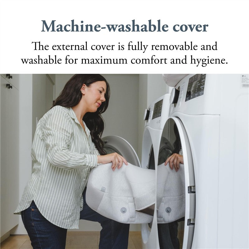 Woman placing the Inglesina Elysia Nursing Pillow in a washing machine, highlighting its machine-washable cover feature.