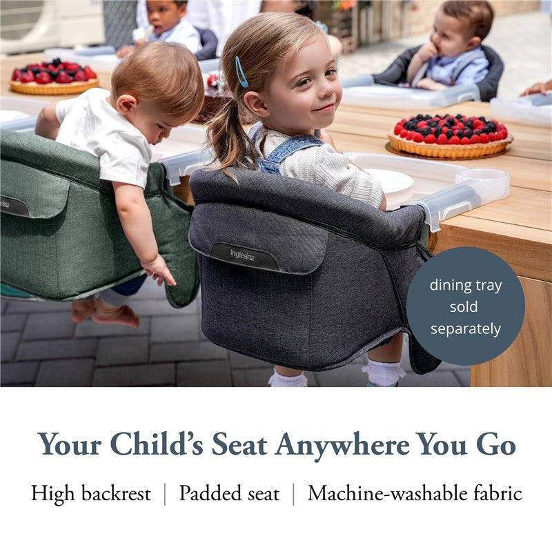 Charcoal gray Inglesina Fast Table Chair with high backrest and padded seat, used by children at a dining table.