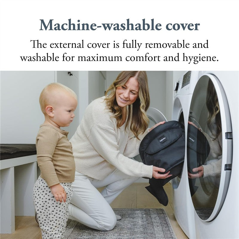 A woman kneels by a washing machine, placing a removable black cover inside while a toddler watches.