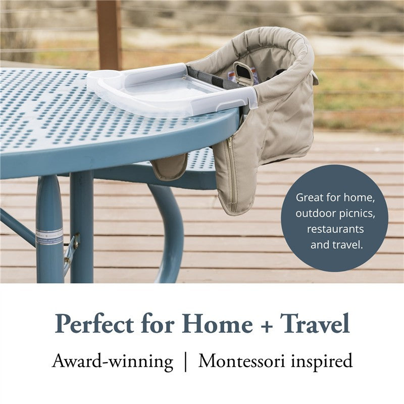 Inglesina Fast Table Chair in Stone Gray Melange attaches to a blue table, featuring a tray and soft fabric sides, suitable for travel.