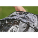 Inglesina Quid³ stroller raincover with water droplets on a transparent surface, being held by a hand outdoors.