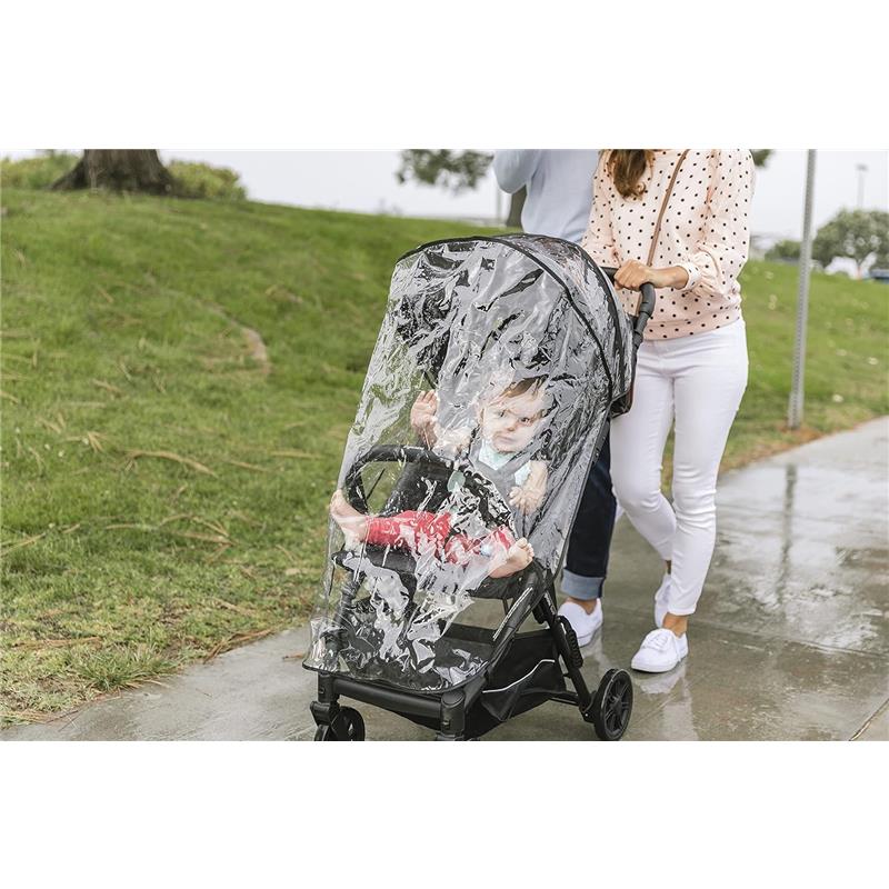 Raincover for the Inglesina Quid³ stroller protects a child inside as a parent pushes it along a wet sidewalk.