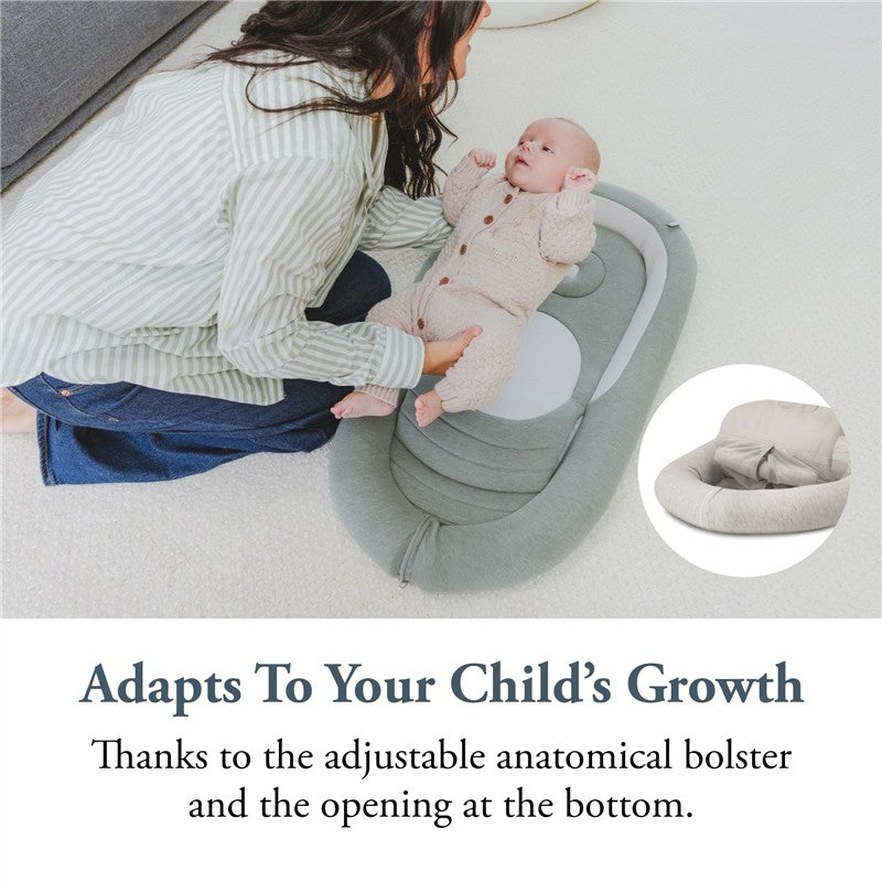 Mom sits on the floor with a baby in a beige onesie, near an Inglesina Welcome Pod Lounger in Balance Green, highlighting its adjustable features.