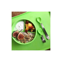 Aqua IPlay Learning Spoon Set with two green spoons beside a divided bowl containing yogurt, chopped fruits, and nuts.